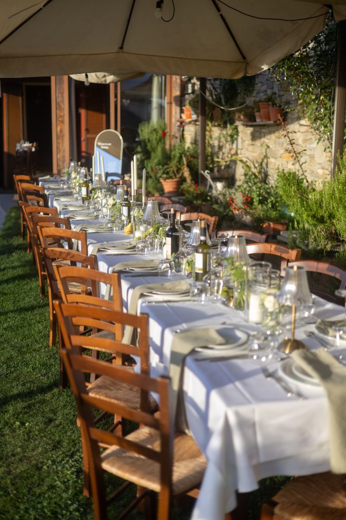 Gedekte dinertafel met witte bloemen en kaarsen op de binnenplaats in Piemonte